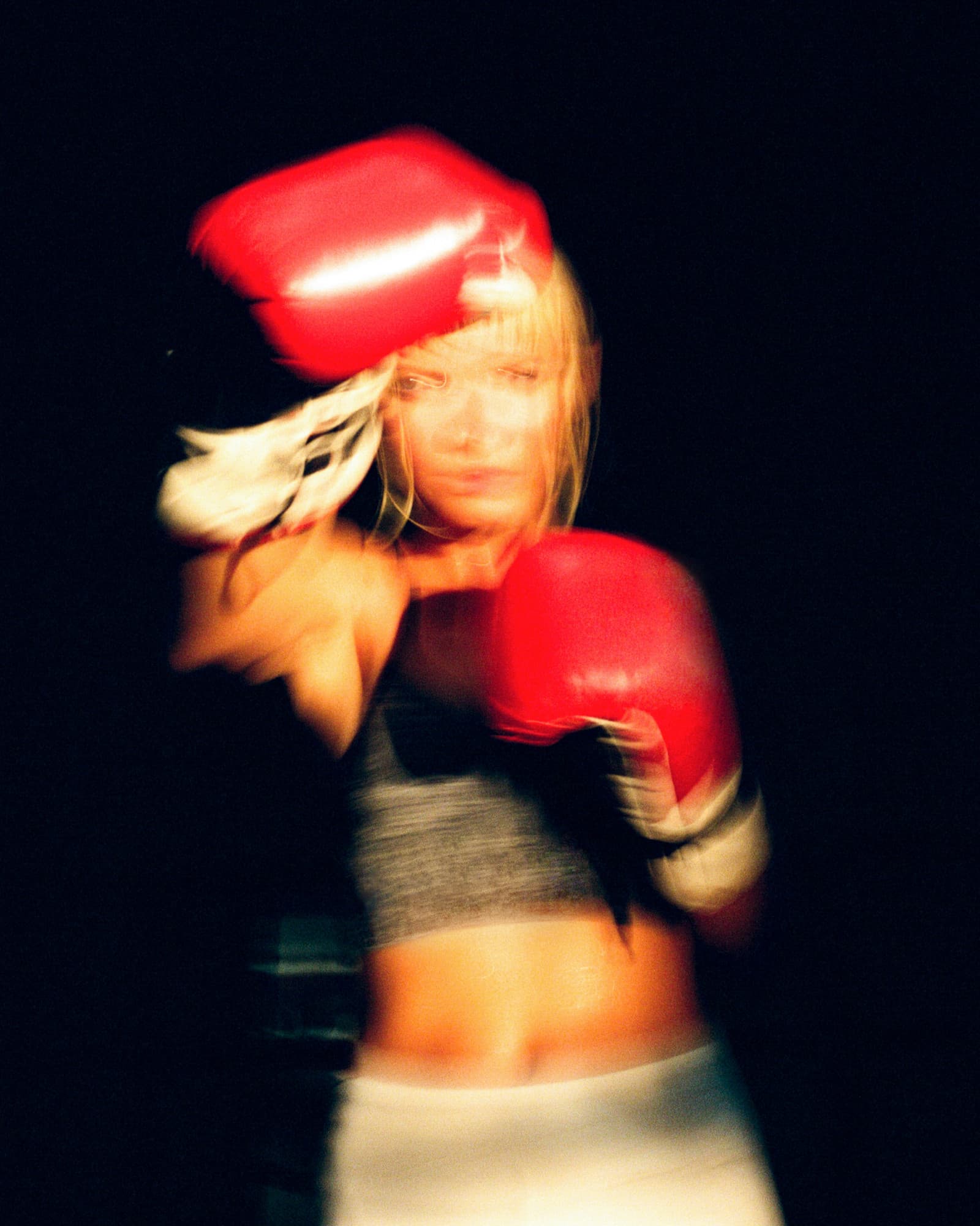 Motion-blurred boxer wearing red gloves against a dark background