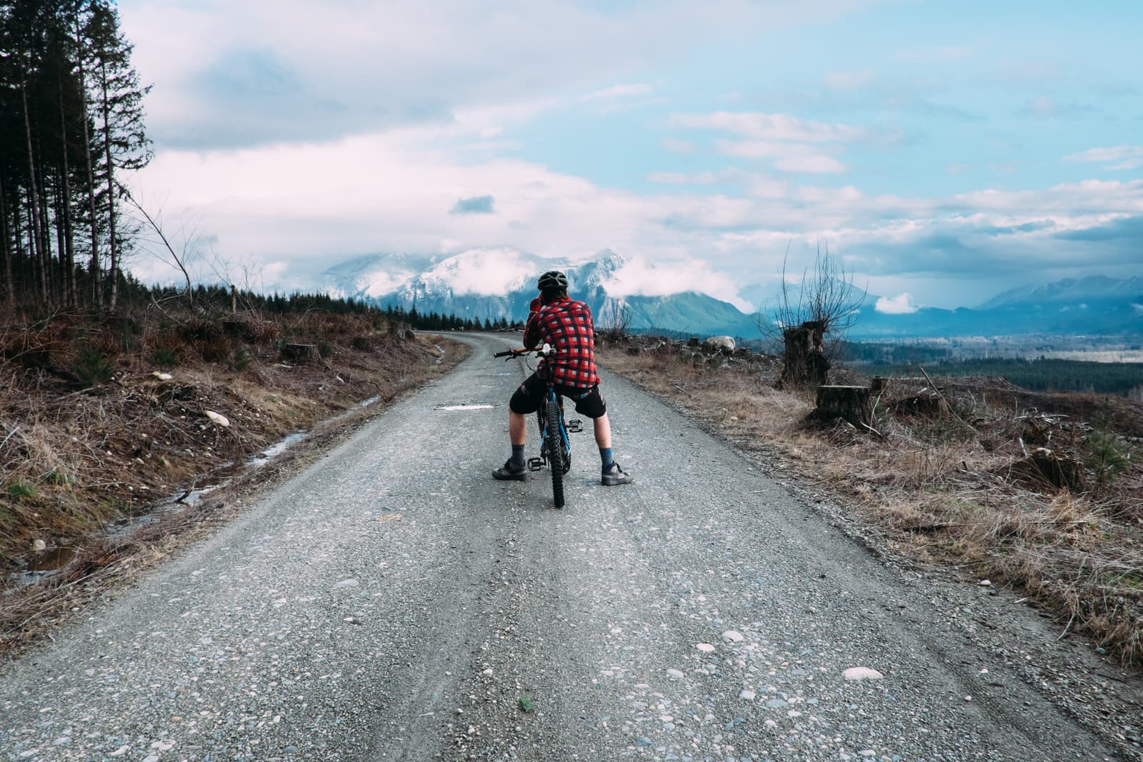 Cyclist on a gravel road facing distant mountains
